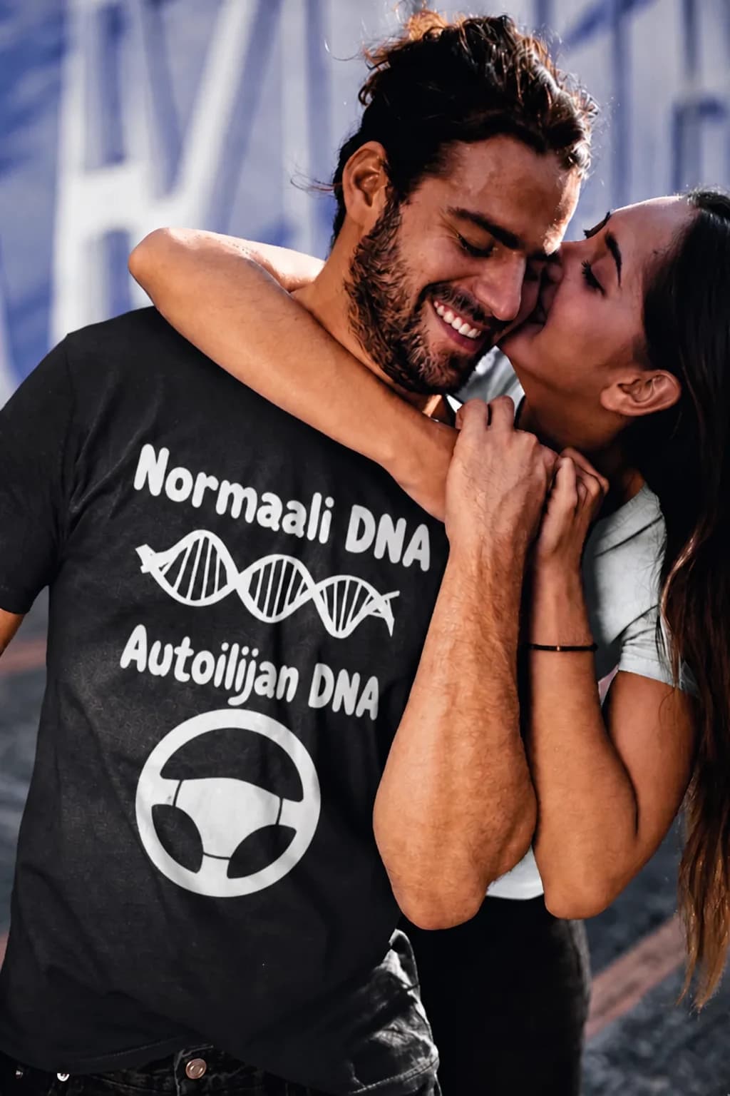 Mies mustassa T-paidassa autoilijalle, tekstit ”Normaali DNA” ja ”Autoilijan DNA” sekä DNA-kierre