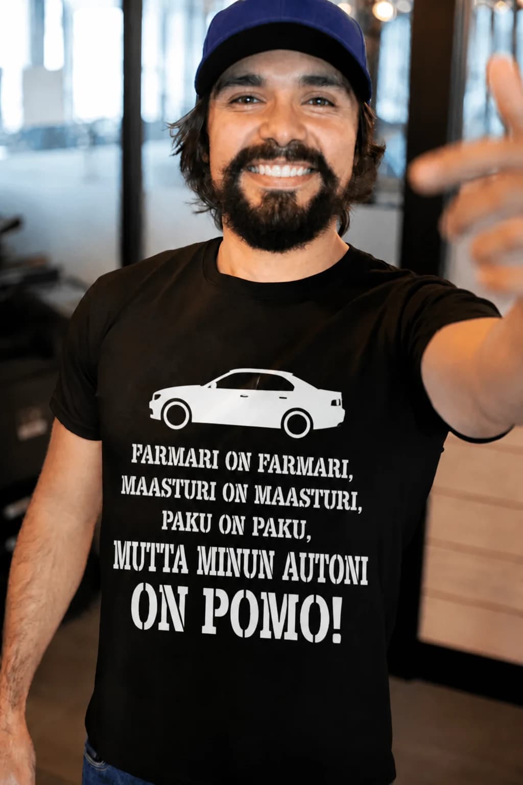Mies mustassa T-paidassa autoilijalle, teksti ”Farmari on farmari… mutta minun autoni on pomo!”