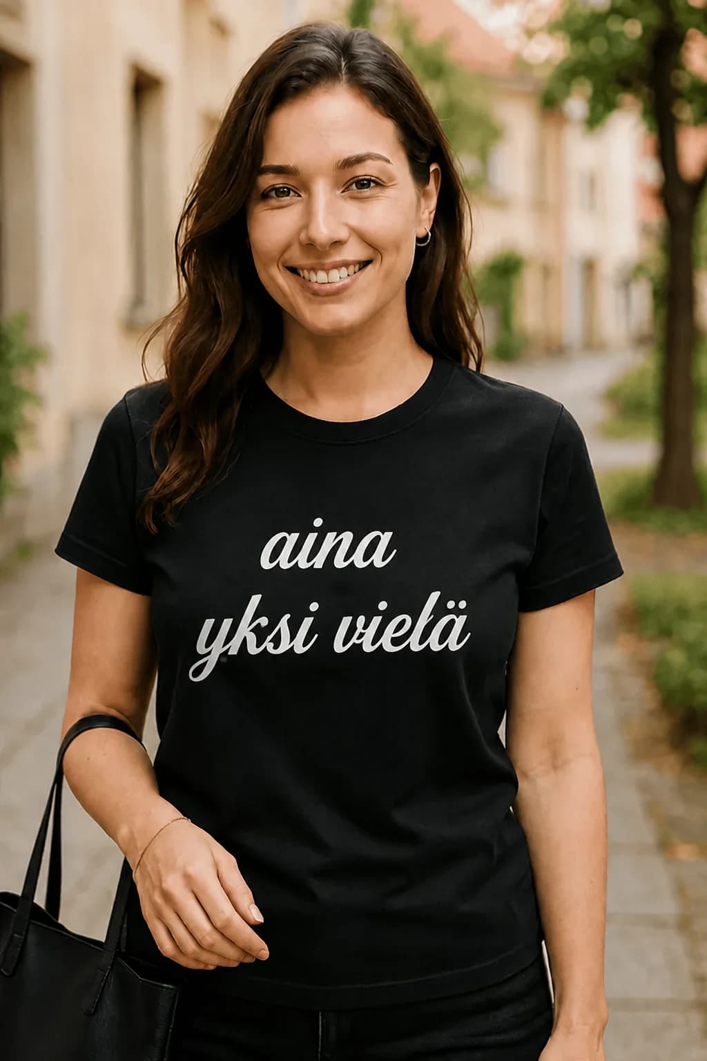 Nainen mustassa T-paidassa, jossa käsialafontilla teksti ”aina yksi vielä” – hauska T-paita juhlijalle