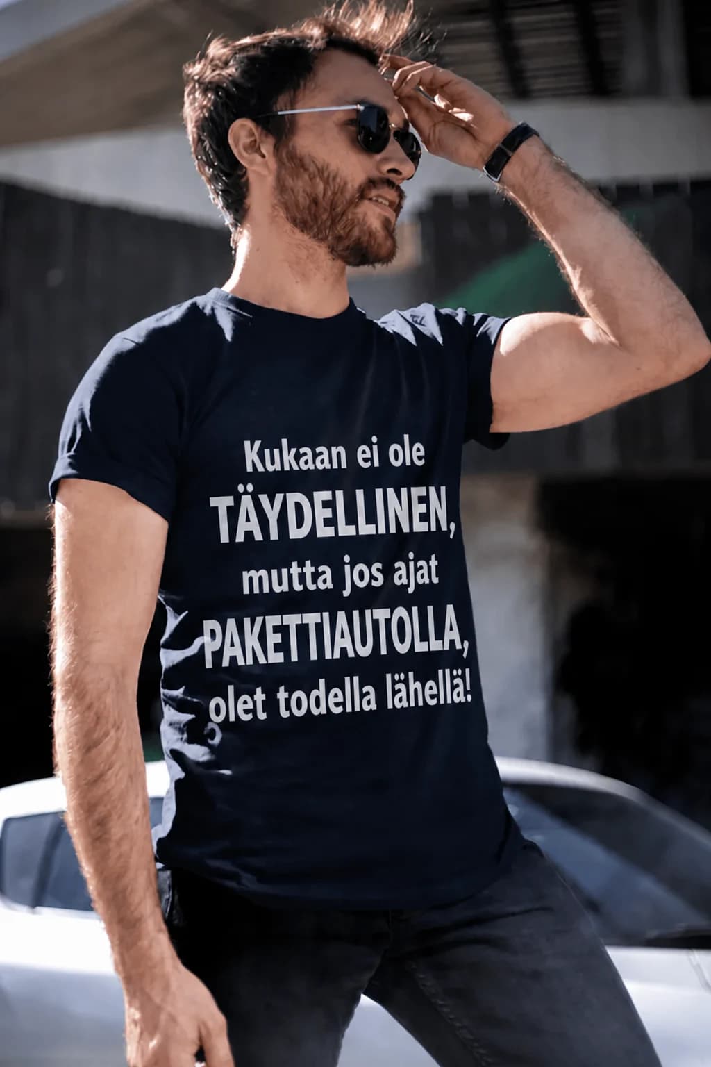 Mies tummassa T-paidassa, jossa teksti Kukaan ei ole täydellinen mutta jos ajat – T-paita autoilijalle omalla tekstillä