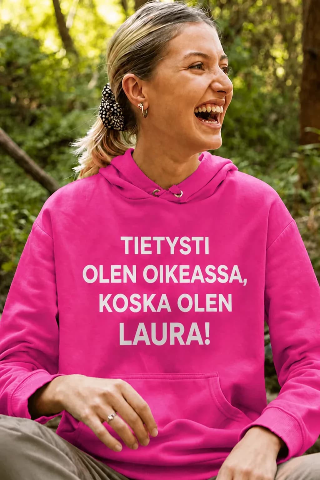 Nainen pinkissä hupparissa, jossa teksti ”Tietysti olen oikeassa, koska olen” ja nimi – nimikoitava huppari