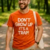 Hauska t-paita Älä kasva aikuiseksi lahjaksi, jossa teksti DON'T GROW UP IT'S A TRAP!